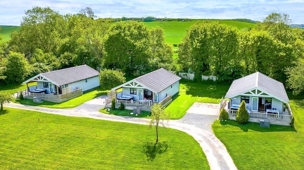 Trois charmantes maisons de campagne, chacune dotée d’une véranda attenante, et entourées de champs verdoyants et d’arbres luxuriants.
