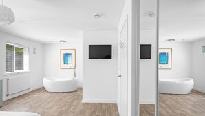Un bagno moderno con due vasche da bagno autonome, uno specchio grande e opere d'arte alle pareti.
