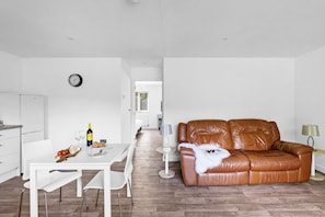 Un espace de vie moderne comprenant un coin repas, un canapé en cuir marron et une cuisine.