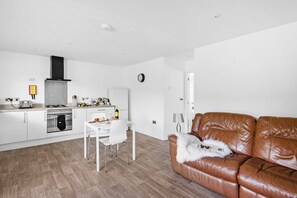 Une cuisine moderne avec des meubles blancs, une cuisinière à gaz et un coin repas comprenant une table et des chaises blanches.