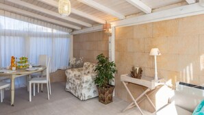 Een moderne woonkamer met een eethoek, met een houten plafond, een grote potplant en een witte bank.