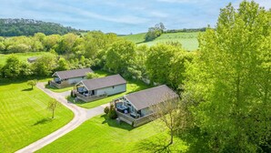 Ein ländliches Anwesen mit drei Ferienhäusern, jedes mit einer Terrasse und Sitzgelegenheiten im Freien.