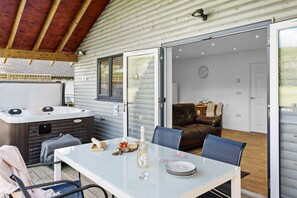 A cozy cabin with a hot tub, a dining area with a table set for two, and a living room with a brown leather sofa.