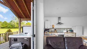 Ein gemütlicher Sitzbereich im Freien mit Whirlpool, einer Holzterrasse und Blick auf eine moderne Küche mit Herd, Backofen und Spüle.