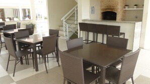 A dining area with a brick fireplace, wicker chairs, and a tiled floor.