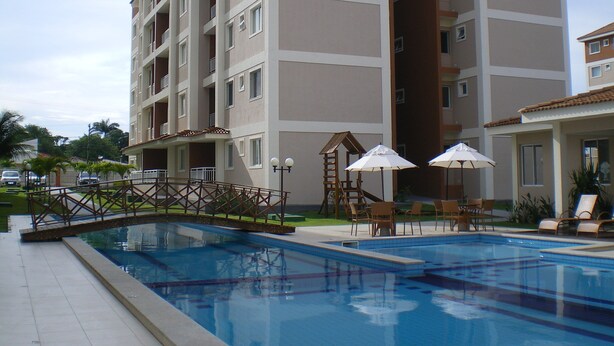 A multi-story hotel with a swimming pool, outdoor seating, and a small bridge.