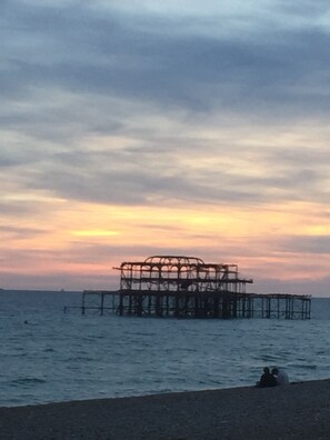 A pier structure extending into the water with a sunset in the background.