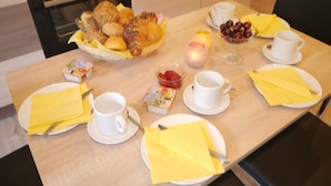 Colazione con diversi dolci, frutta e bevande su un tavolo di legno.