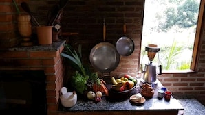Una cocina con pared de ladrillo, una ventana y varios utensilios de cocina y productos frescos en la encimera.
