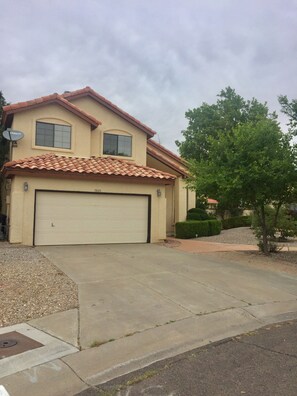 A two-story house with a garage, a satellite dish, and a well-maintained lawn.