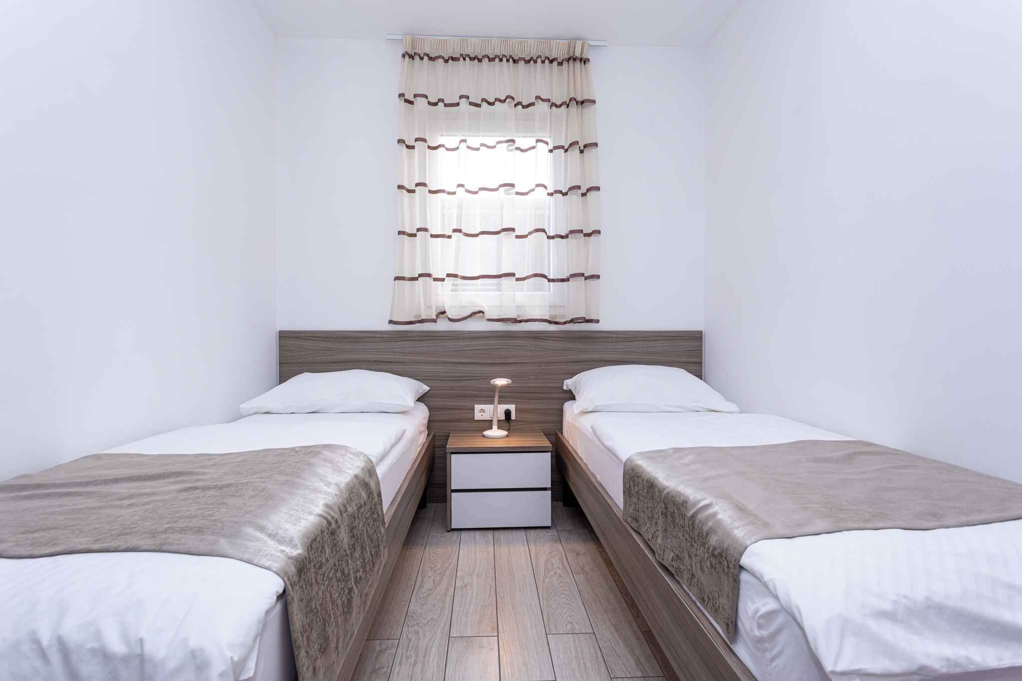A twin room with two beds, a nightstand with a lamp, and a window with curtains.