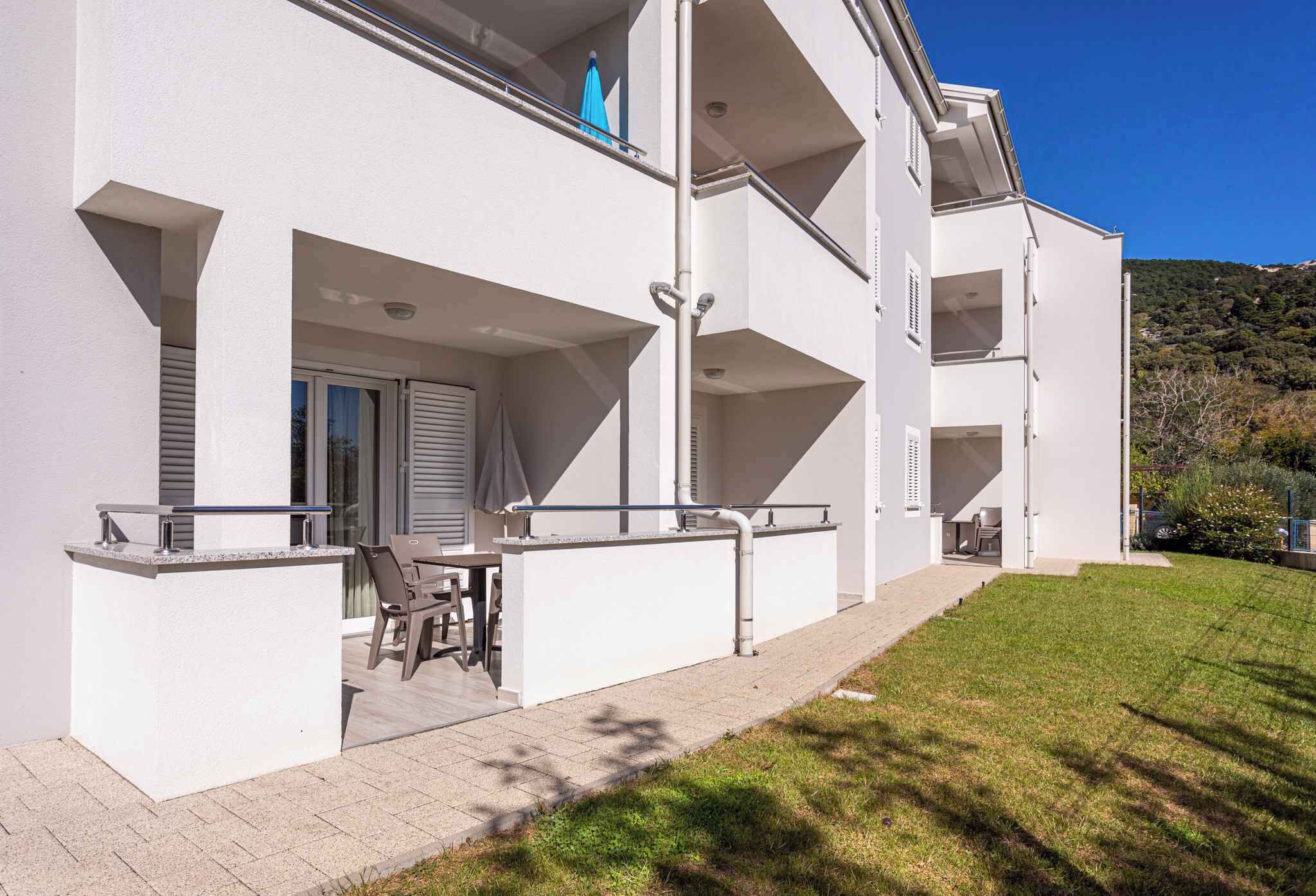 A modern two-story building with a balcony, outdoor seating, and a well-maintained lawn.