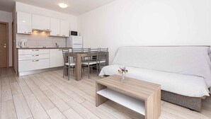 Una cocina moderna con armarios blancos, una mesa de comedor con sillas y un sofá en la sala.