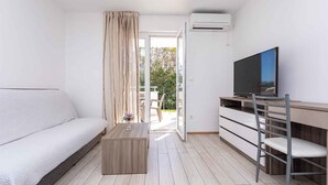 Une pièce moderne et bien éclairée, comprenant un canapé, un téléviseur, un bureau et une chaise.