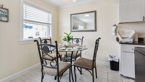 A dining area with a round table, four chairs, a potted plant, and a window with blinds. - 1 block to beach & boardwalk | Central Downtown (Virginia Beach)