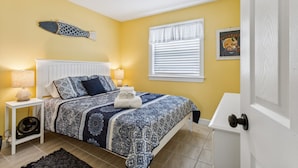 A bedroom with a bed, two bedside tables with lamps, a wall-mounted fish decoration, a window with blinds, and a door. - 1 block to beach & boardwalk | Central Downtown (Virginia Beach)