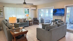 Ein geräumiges Wohnzimmer mit grauem Sofa, einem Couchtisch und einem Fernseher an der Wand.