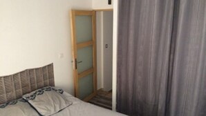 Een slaapkamer met een bed, een houten hoofdbord, een deur en een gordijn.