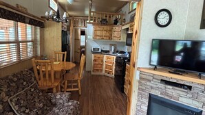 Un acogedor interior de cabaña con comedor de madera, chimenea y cocina con armarios de madera.