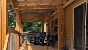 Una terraza techada con barandas de madera, una mesa con sillas y un gran ventanal corredera.