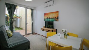 Et værelse med en sofa, et spisebord med stole, et billede og en aircondition.