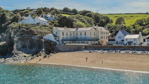 A coastal building with multiple stories, situated on a cliff overlooking a beach. - The Penthouse, 16 At The Beach, Wi-Fi, Sea View (Kingsbridge)