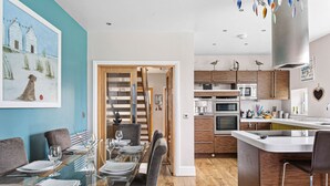 A modern kitchen with wooden cabinets, stainless steel appliances, and a bar area. - The Penthouse, 16 At The Beach, Wi-Fi, Sea View (Kingsbridge)