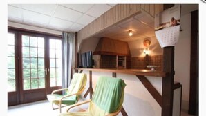 Une pièce dotée d’une grande fenêtre, d’un plafond en bois et d’une chaise recouverte d’un tissu vert.