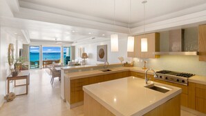 Una cocina moderna con una isla grande, electrodomésticos de acero inoxidable e iluminación colgante.