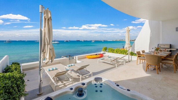 Terraza en la azotea con jacuzzi, sillas de descanso y zona de comedor con vistas al mar.