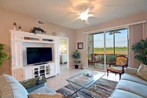 Relax in a spacious living room with a flat-screen TV, comfortable seating area, and sliding glass door leading to a scenic outdoor view.