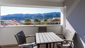Un balcon avec une table et des chaises, donnant sur un paysage montagneux et une piscine.