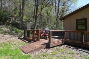 A wooden deck leading to a building with a covered outdoor seating area. - Charming cottage with pond in Heart of New River Gorge (Victor)