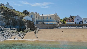 A coastal building with multiple stories, situated on a rocky cliff overlooking a sandy beach. - 11 At The Beach, Torcross - an apartment that sleeps 4 guests in 2 bedrooms (Kingsbridge)