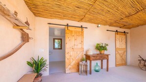 Un interior rústico con puertas de madera, un banco, una mesa con una planta y una bicicleta.