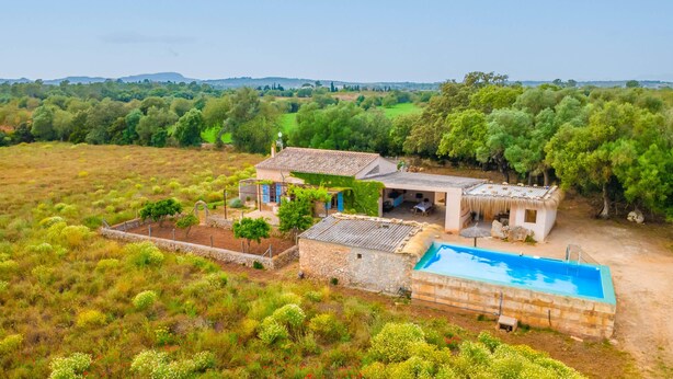 Una villa con piscina, muros de piedra y jardín.