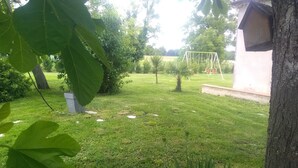 A well-maintained grassy area with a swing set, a birdhouse, and a concrete structure.