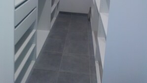 A narrow walk-through closet with white shelving units and drawers.