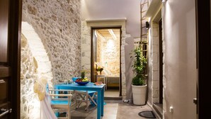 A narrow hallway with a stone wall, a blue table with chairs, and a potted plant. - Alice Residence - Two Storey Luxury Residence in the Heart of Rethymno Old Town (Rethymno)