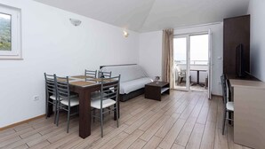 A modern, well-lit room with a dining table, chairs, a sofa, and a TV. - Holiday apartment mit Klimaanlage und Meerblick (Baška)