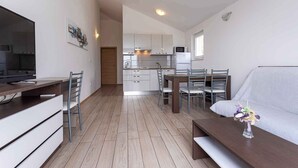 A compact living space with a kitchenette, a dining area, and a seating area with a sofa. - Holiday apartment mit Klimaanlage und Meerblick (Baška)