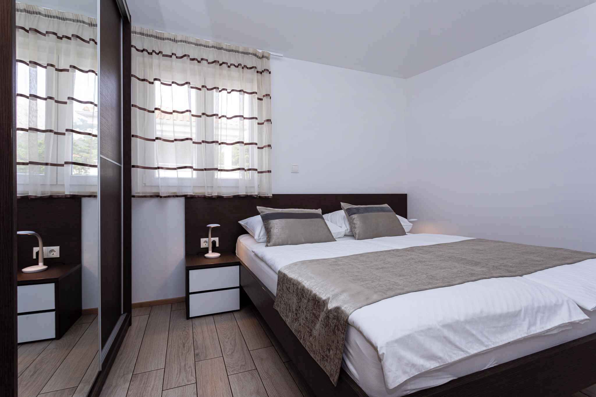 A modern bedroom with a large bed, bedside tables, and a mirror.