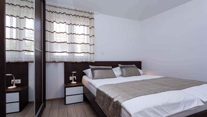 A modern bedroom with a large bed, bedside tables, and a mirror. - Holiday apartment mit Klimaanlage und Meerblick (Baška)
