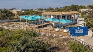 Un restaurant situé en bord de mer, doté d’une terrasse et d’une structure au toit de chaume.