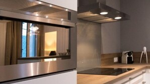 Een moderne keuken met witte kasten, roestvrijstalen apparatuur en een houten aanrecht.