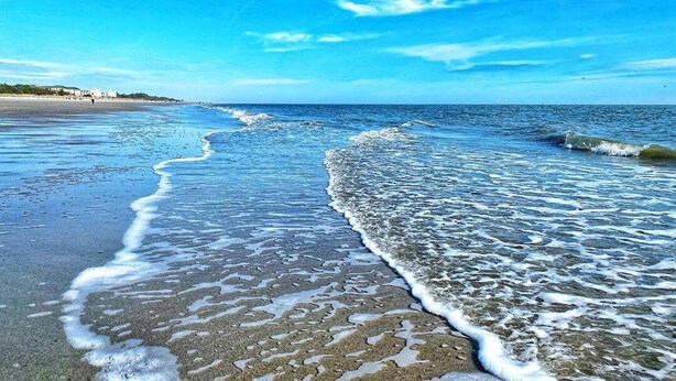 Een strand met helderblauw water en een zandstrand.