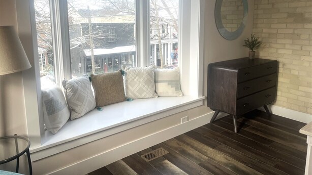 A room with a bay window overlooking a street, a dresser, and a lamp. - Cozy 1-bedroom condo in downtown Saugatuck, perfect for a romantic getaway. (Saugatuck)
