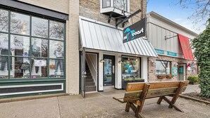 A storefront with a sign reading 'mi coast,' a bench outside, and a building with a brick facade. - Cozy 1-bedroom condo in downtown Saugatuck, perfect for a romantic getaway. (Saugatuck)
