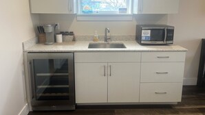 A modern kitchen with a built-in dishwasher, a microwave, a sink, and a window above the sink. - Cozy 1-bedroom condo in downtown Saugatuck, perfect for a romantic getaway. (Saugatuck)