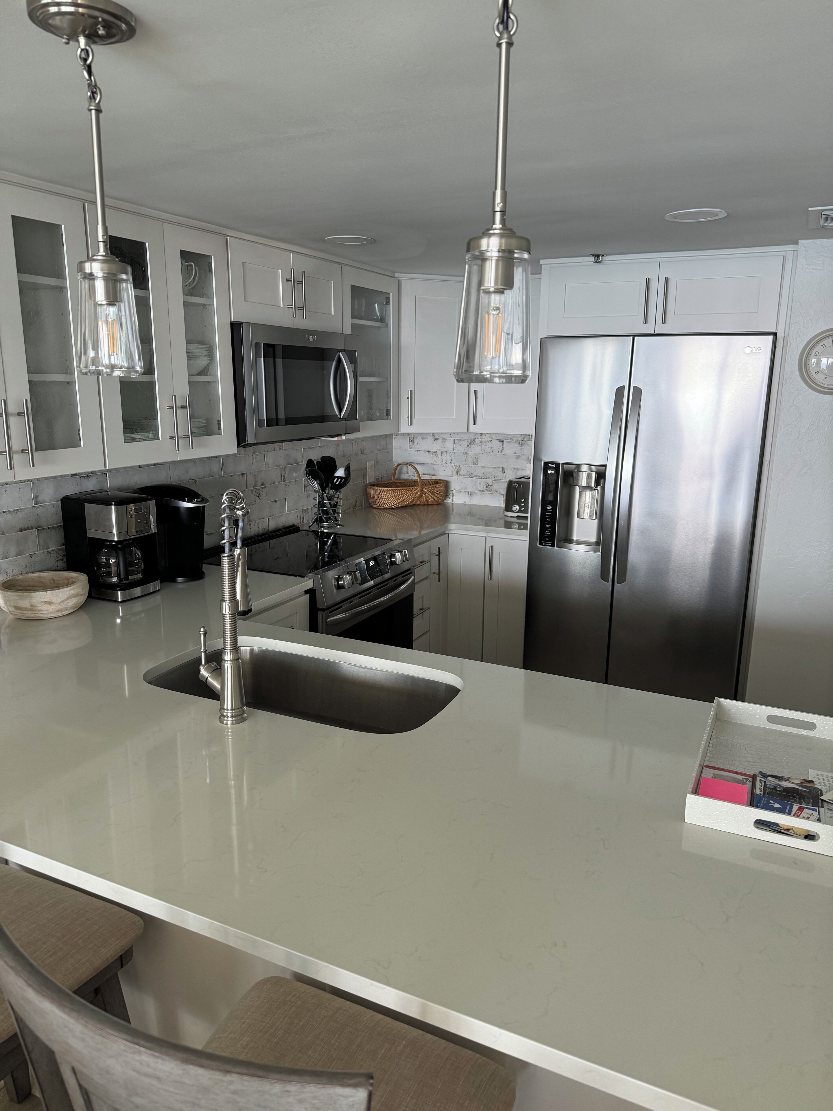 A modern kitchen with stainless steel appliances, a large island with a sink, and pendant lighting.